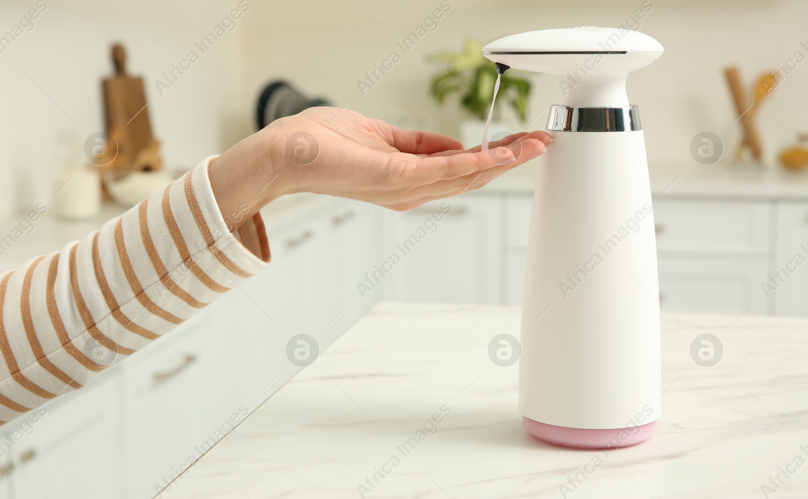 Photo of Woman using automatic soap dispenser in kitchen, closeup