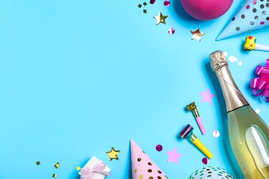 Photo of Flat lay composition with birthday decor and bottle of sparkling wine on light blue background, space for text