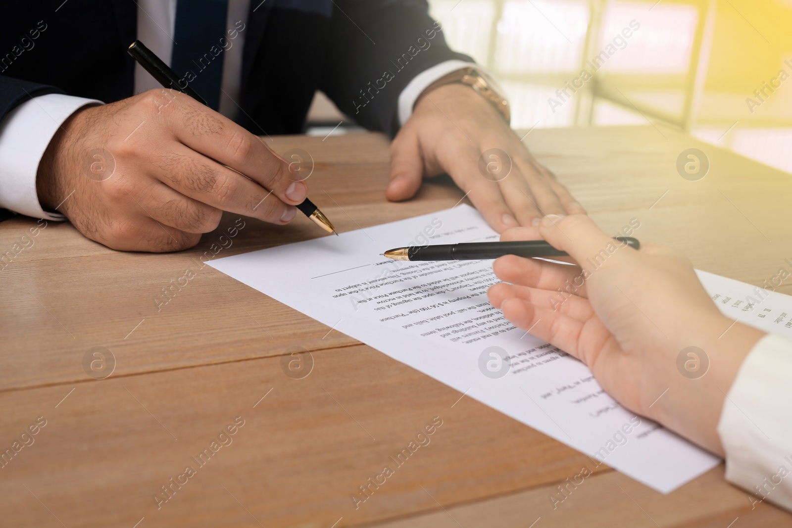 Image of Man signing document at wooden table in office, closeup. Insurance concept