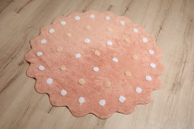 Photo of Round pink rug with polka dot pattern on wooden floor
