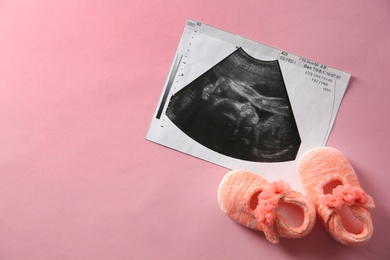 Photo of Ultrasound picture and baby shoes on color background, top view with space for text