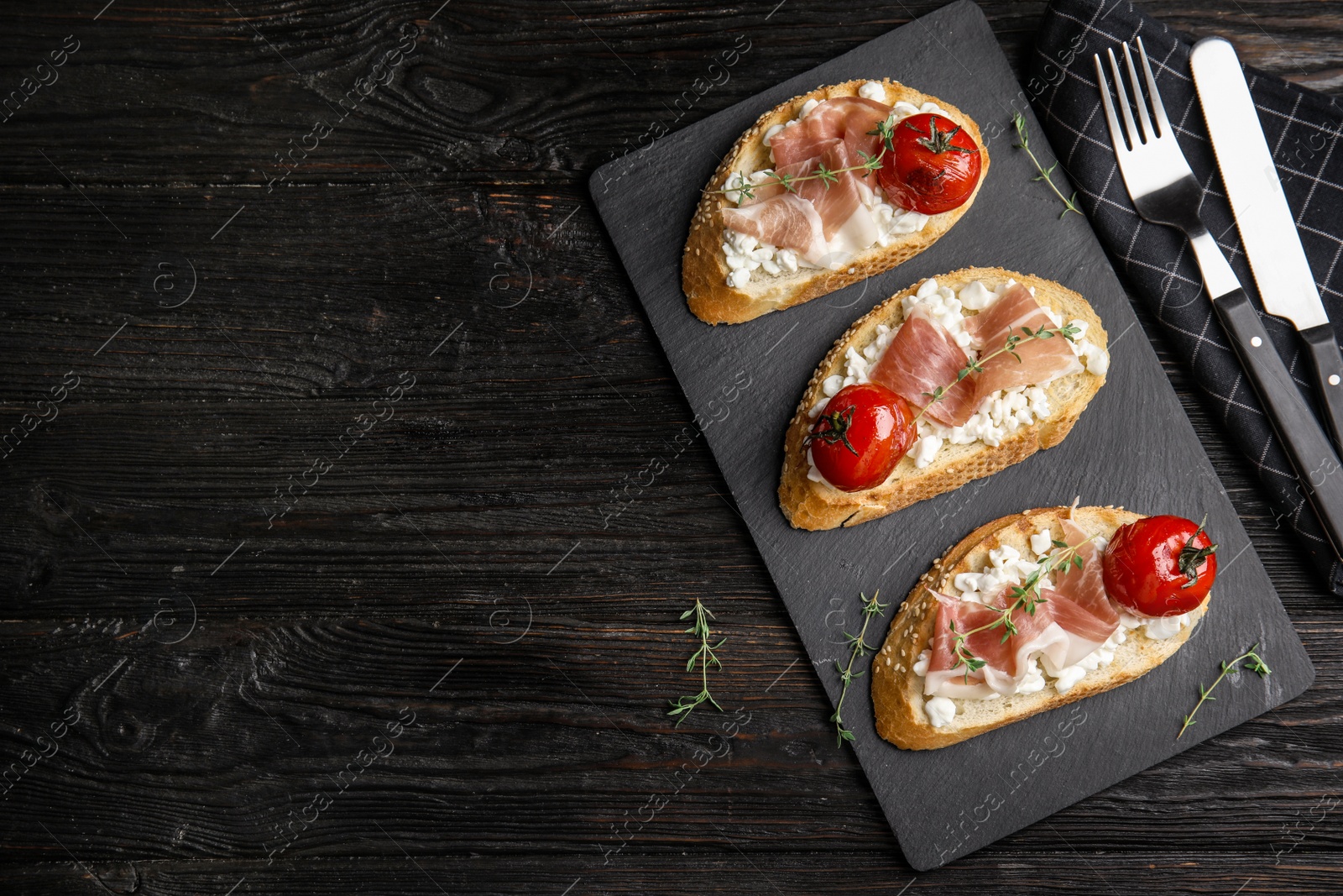 Photo of Flat lay composition with delicious bruschettas on black wooden table, space for text