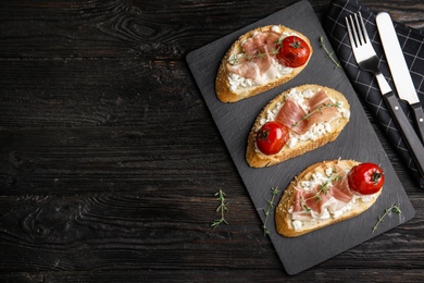 Photo of Flat lay composition with delicious bruschettas on black wooden table, space for text