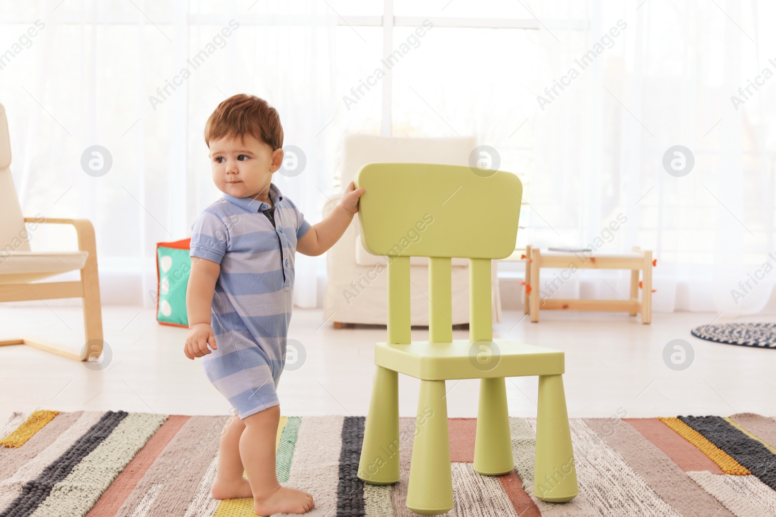 Photo of Cute baby with chair at home. Learning to walk