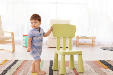 Photo of Cute baby with chair at home. Learning to walk