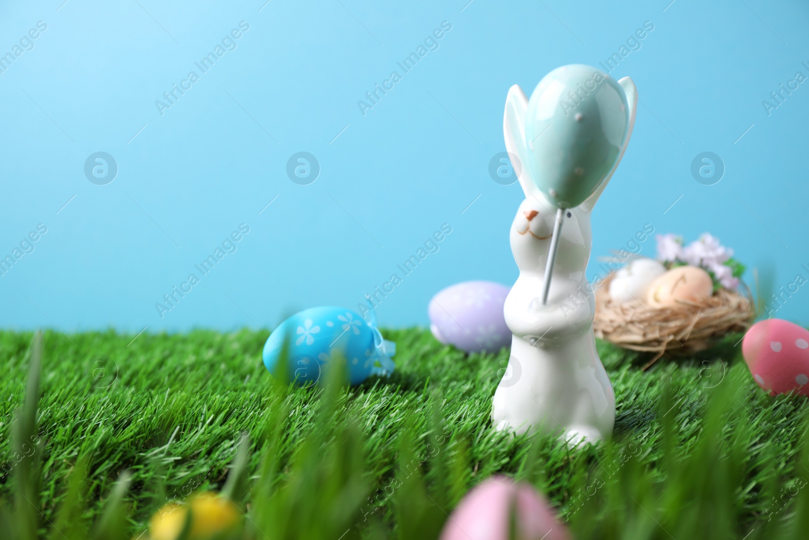 Photo of Easter bunny and painted eggs on green grass, space for text