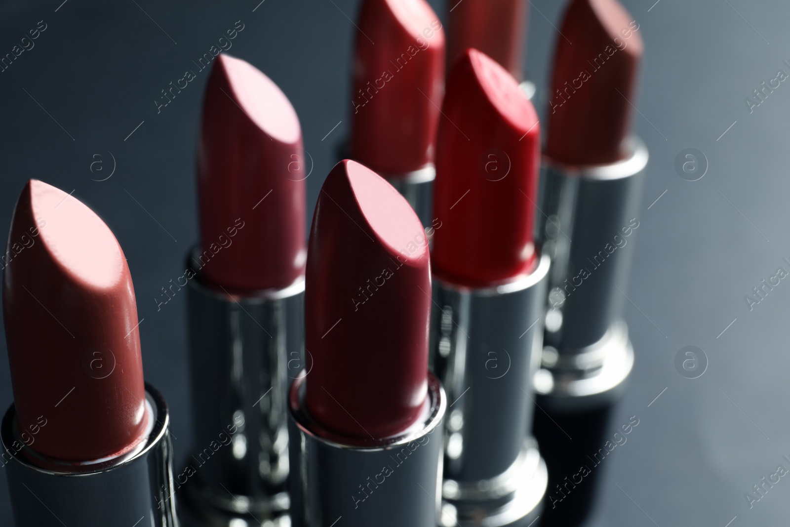 Photo of Set of different lipsticks on grey background, closeup. Cosmetic product