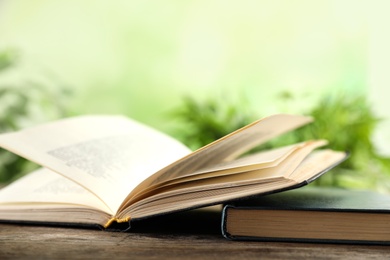 Open hardcover book on wooden table against blurred background