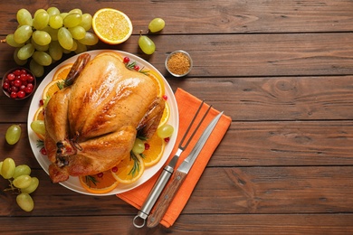 Platter of cooked turkey with garnish on wooden background, flat lay. Space for text