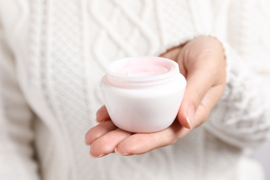 Photo of Woman holding jar of moisturizing cream, closeup. Winter skin care cosmetic