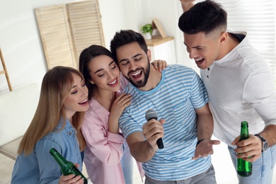 Happy friends singing karaoke together at home