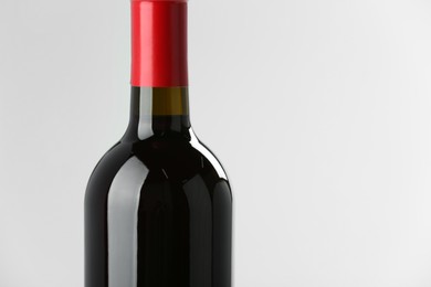 Photo of Bottle of expensive red wine on light background, closeup. Space for text