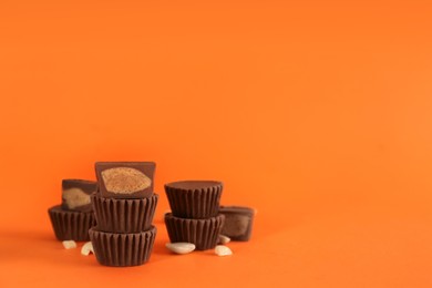 Photo of Sweet peanut butter cups on orange background. Space for text