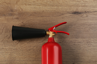 Photo of Fire extinguisher on wooden background, top view