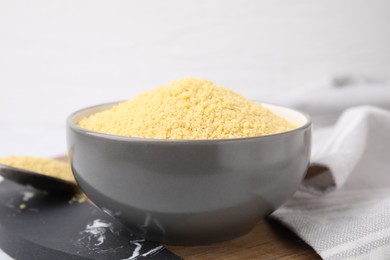 Photo of Raw couscous in bowl on table, closeup