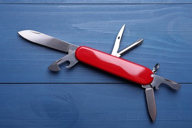 Modern compact portable multitool on blue wooden table, top view