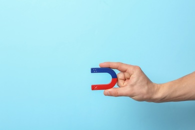 Photo of Man holding magnet on color background, closeup. Space for text