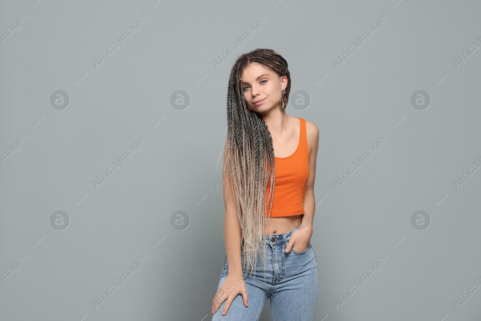 Photo of Beautiful woman with long african braids on grey background, space for text