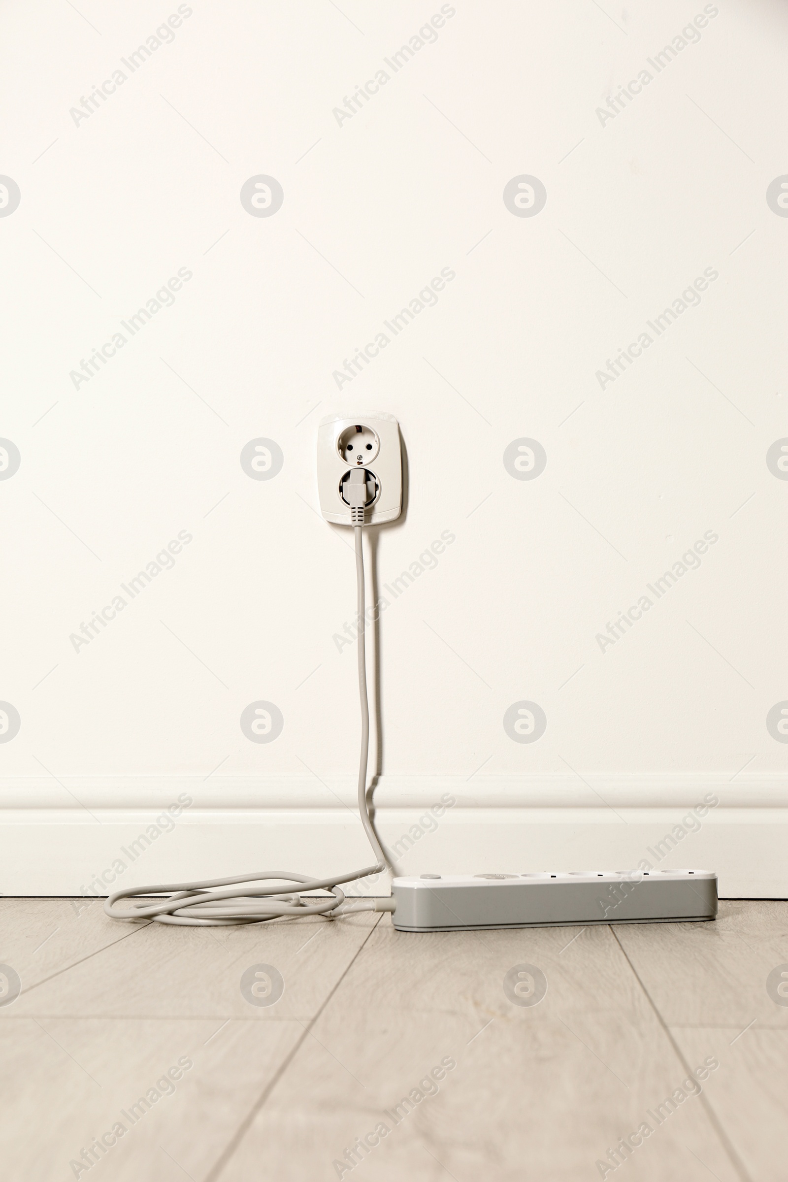 Photo of Extension cord with power plug in socket indoors. Electrician's professional equipment