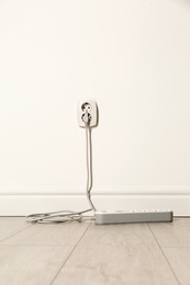 Photo of Extension cord with power plug in socket indoors. Electrician's professional equipment