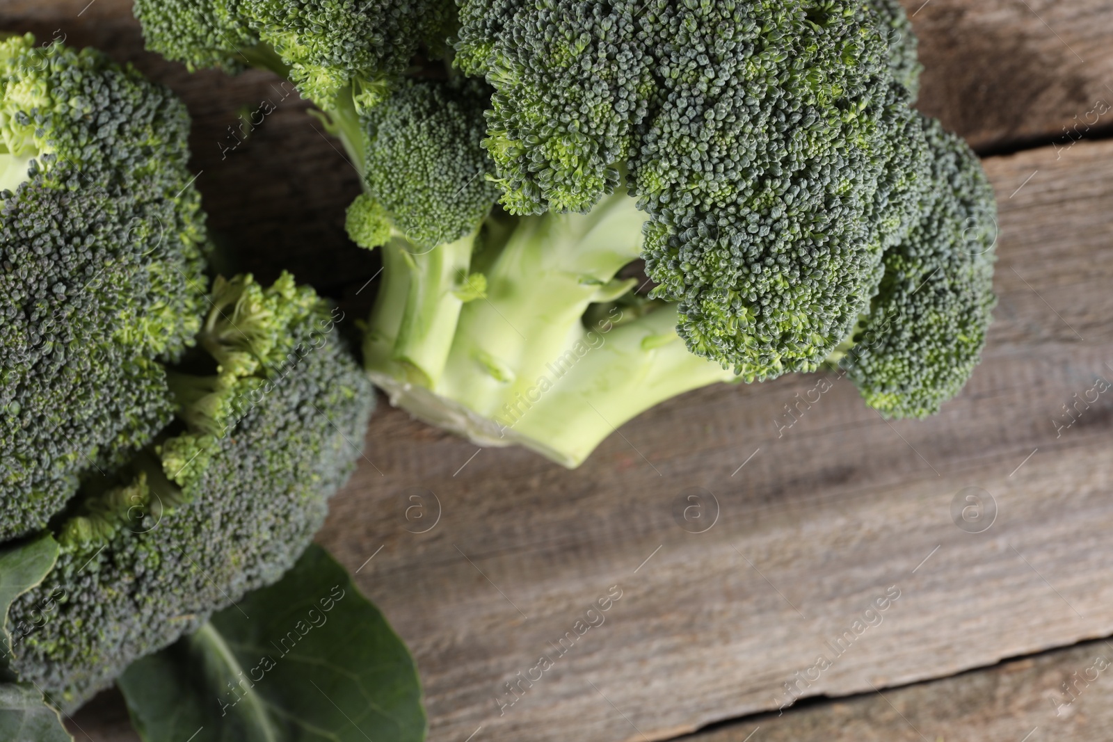 Photo of Fresh raw broccoli on wooden table, top view and space for text