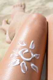Photo of Sun drawn with sunscreen on woman's leg at beach, closeup