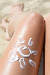 Sun drawn with sunscreen on woman's leg at beach, closeup