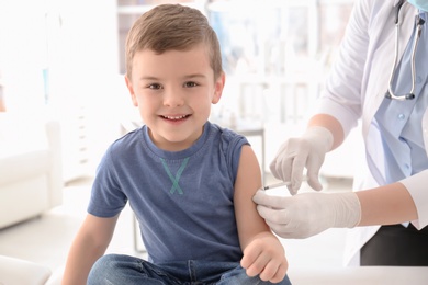 Photo of Doctor vaccinating little boy in hospital