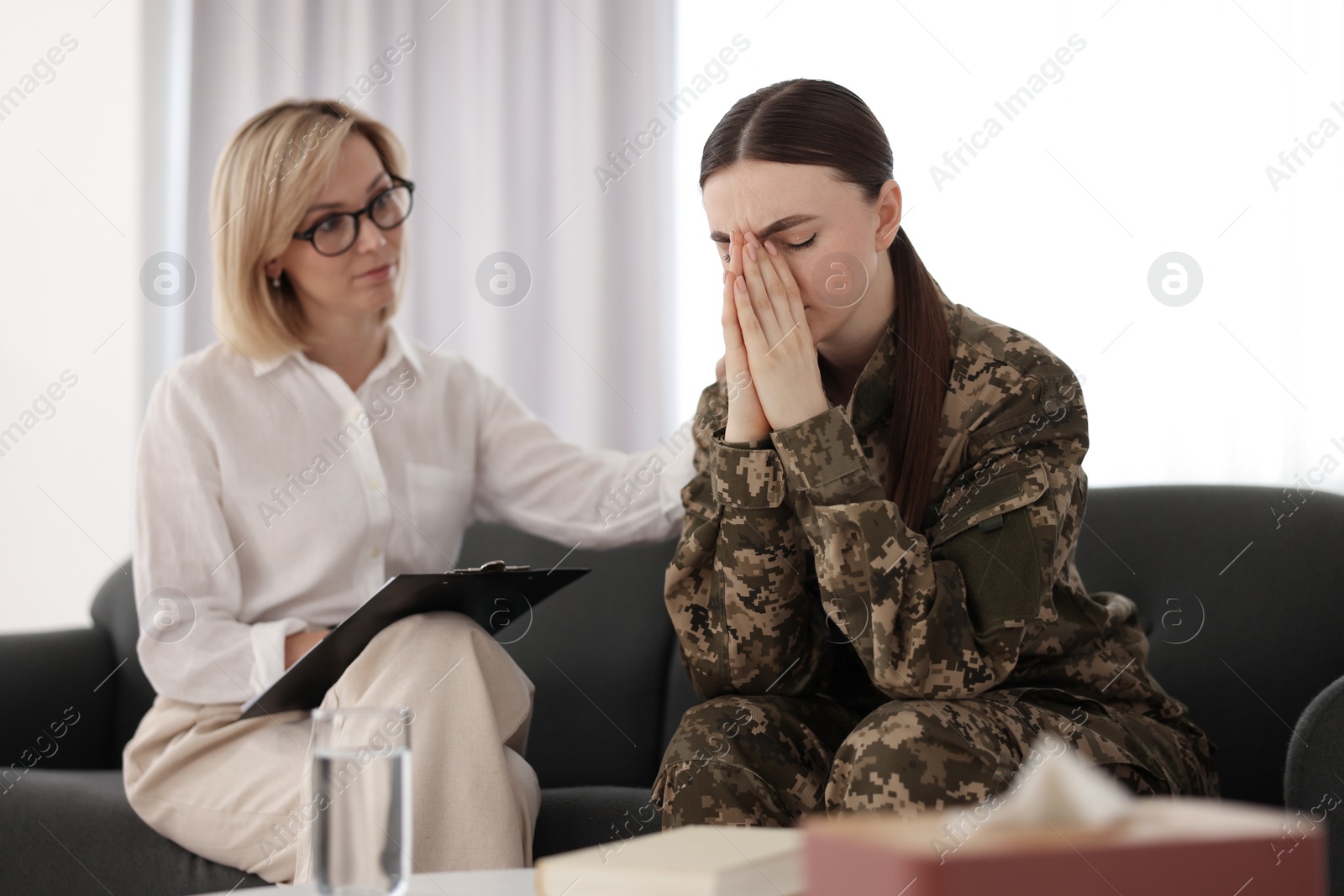 Photo of Psychotherapist working with military woman on sofa in office