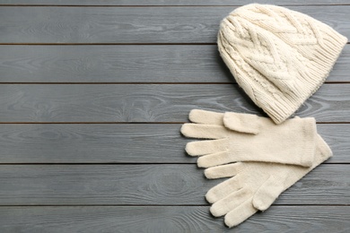 Stylish gloves and hat on grey wooden background, flat lay. Space for text