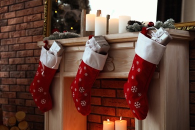 Decorative fireplace with Christmas stocking and gifts in stylish room interior