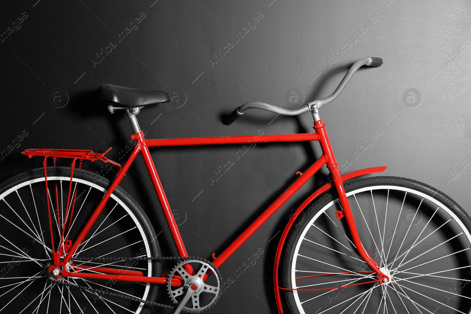 Photo of Red bicycle hanging on black wall, closeup