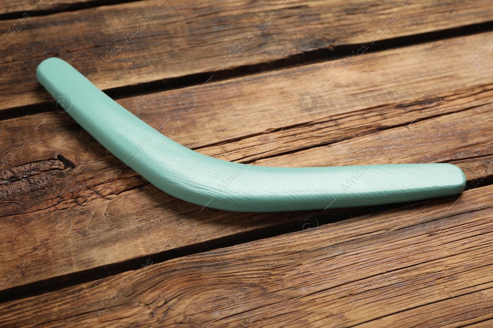 Photo of Turquoise boomerang on wooden background. Outdoors activity