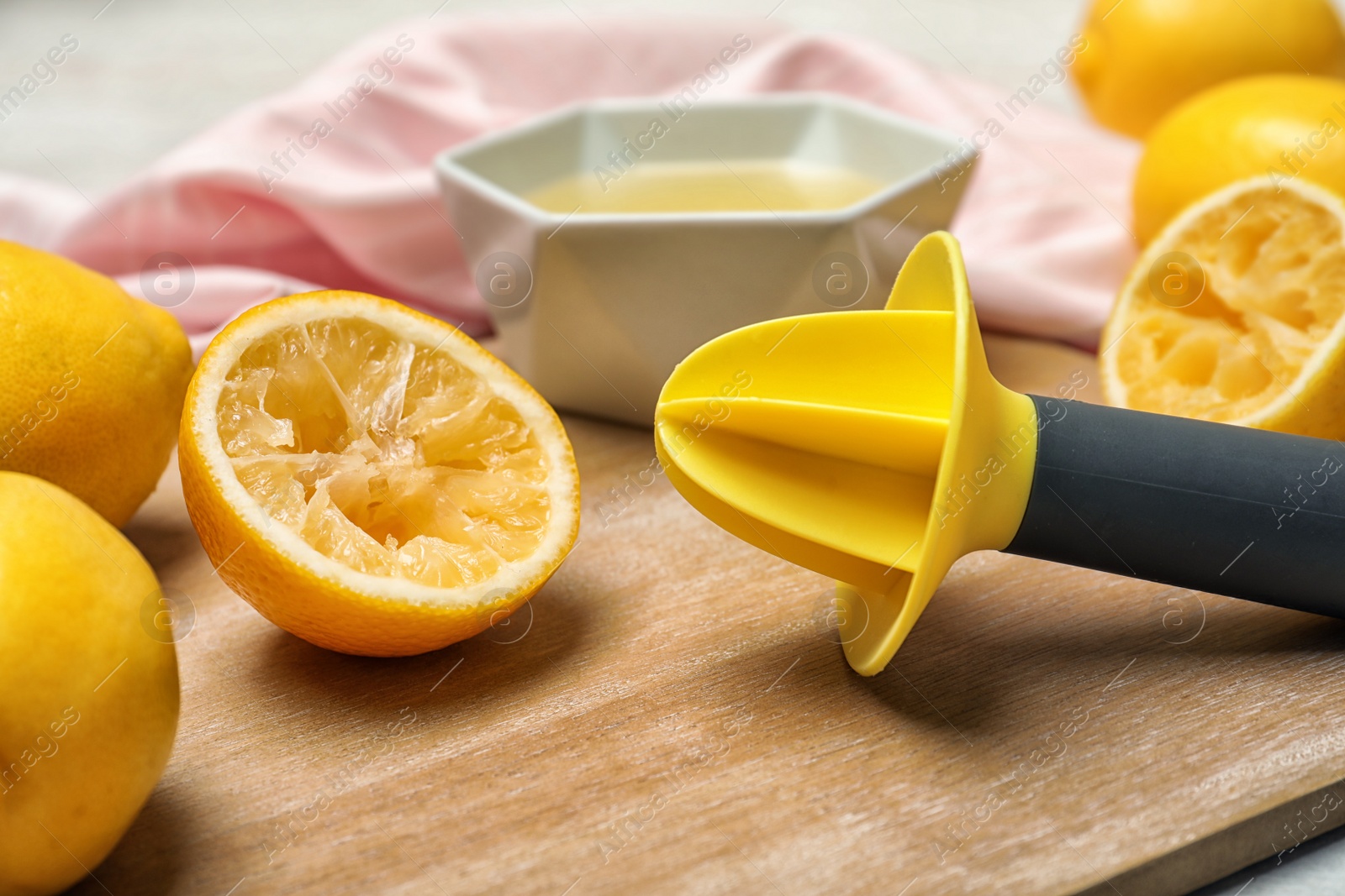 Photo of Wooden board with plastic juicer and squeezed lemon half on board