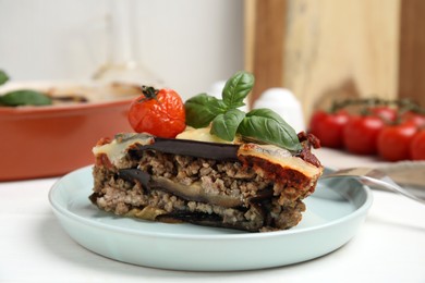 Photo of Plate of delicious eggplant lasagna served on white wooden table