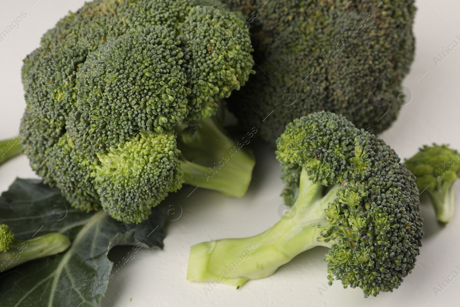 Photo of Fresh raw broccoli on white table, closeup