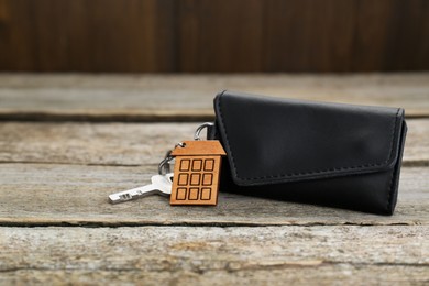 Photo of Leather case with key on old wooden table. Space for text