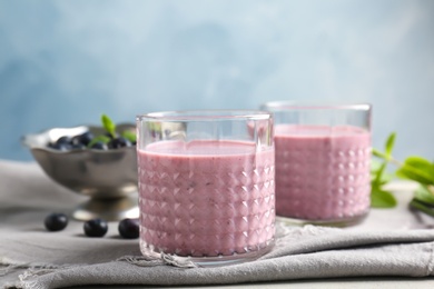 Glasses with healthy detox smoothie and blueberries on table