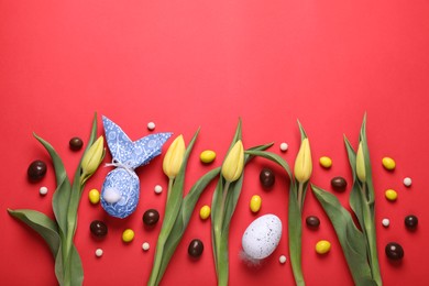 Flat lay composition with Easter bunny made of wrapping paper and egg on red background. Space for text