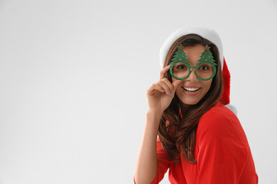 Beautiful woman wearing Santa hat and festive glasses on white background. Christmas party