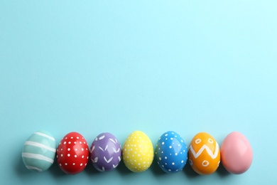 Flat lay composition of painted Easter eggs on color background, space for text