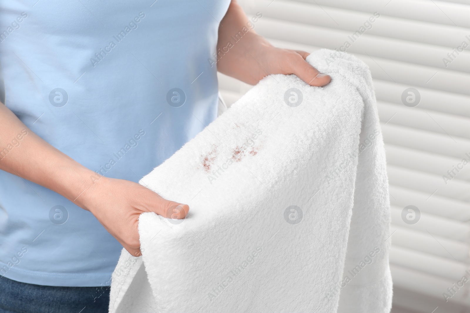 Photo of Woman holding terry towel with makeup spot indoors, closeup