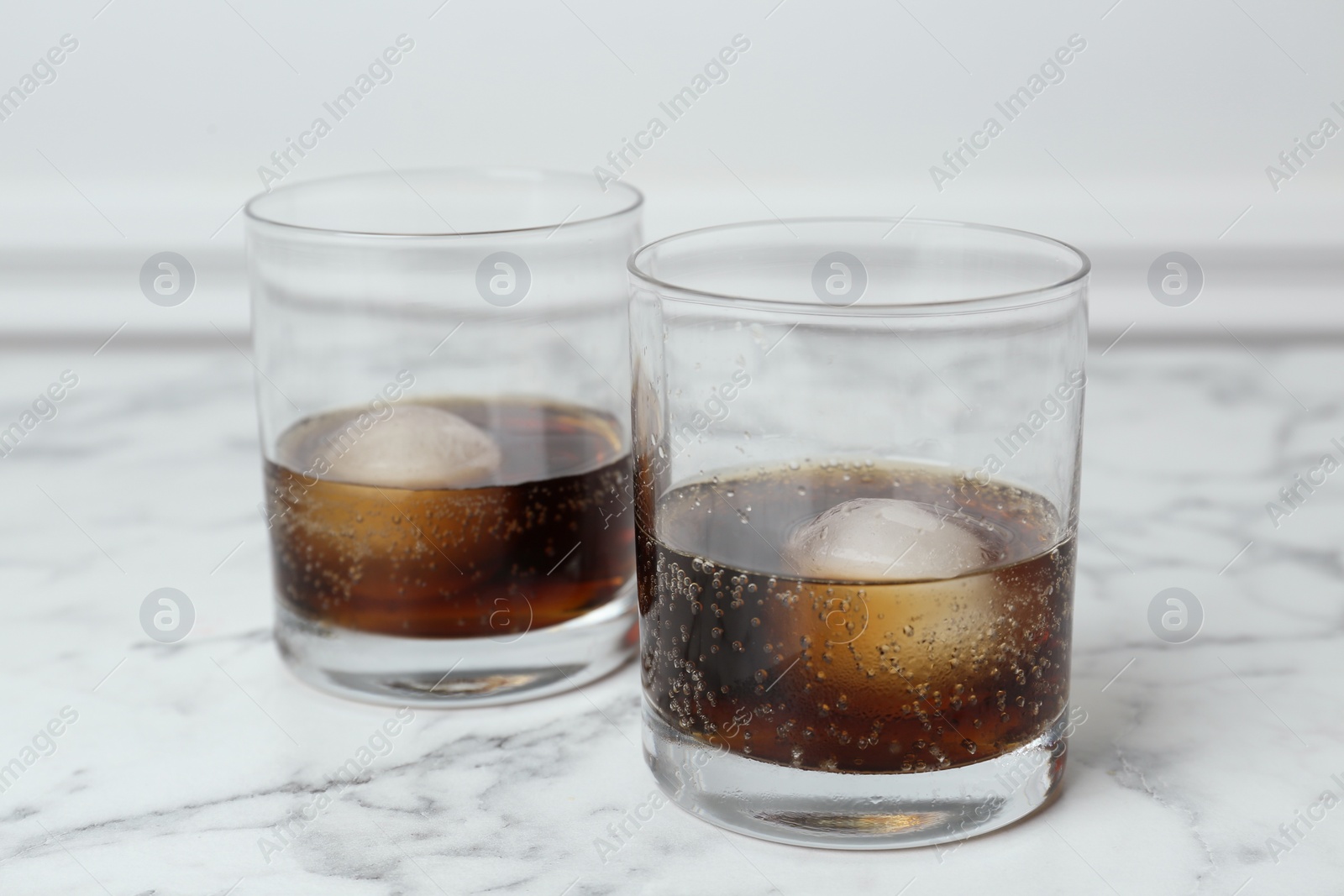 Photo of Cocktails with ice balls on white marble table