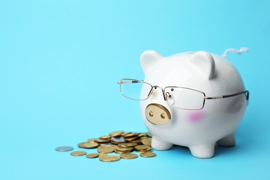 Photo of Piggy bank with glasses and coins on color background. Space for text