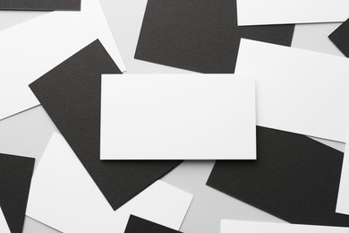 Photo of Blank black and white business cards on light background, flat lay. Mockup for design