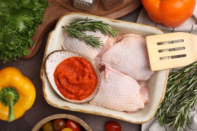 Photo of Flat lay composition with marinade, raw chicken, rosemary and other products on table