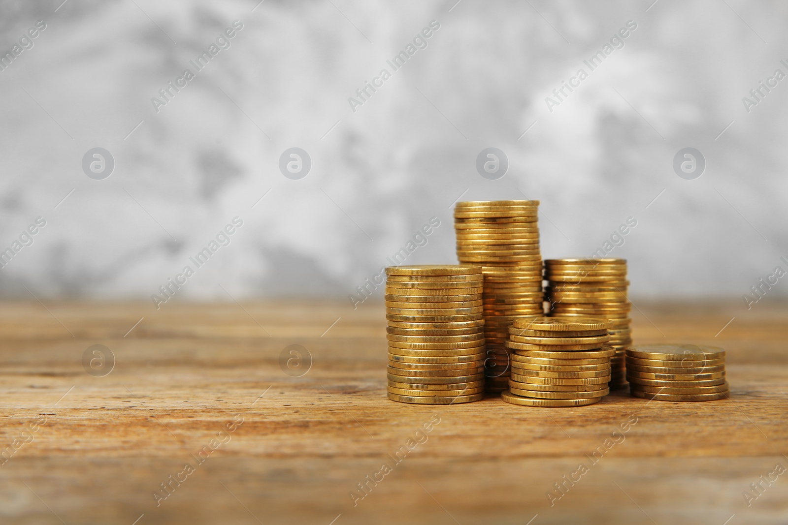 Photo of Many stacks of coins on table against blurred background, space for text