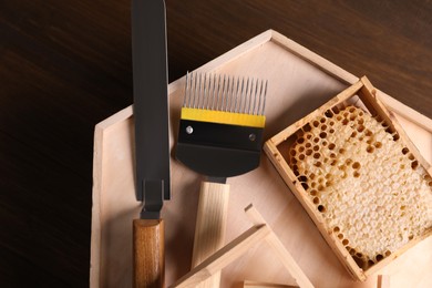 Photo of Honeycomb frames and beekeeping tools on wooden table, top view