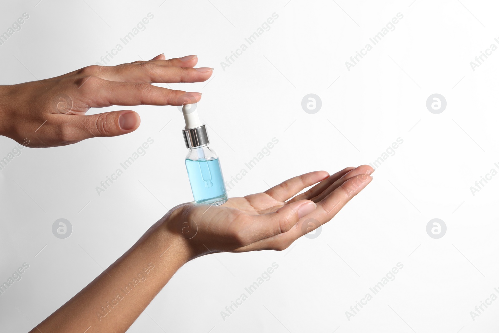 Photo of Woman with bottle of cosmetic serum on white background, closeup