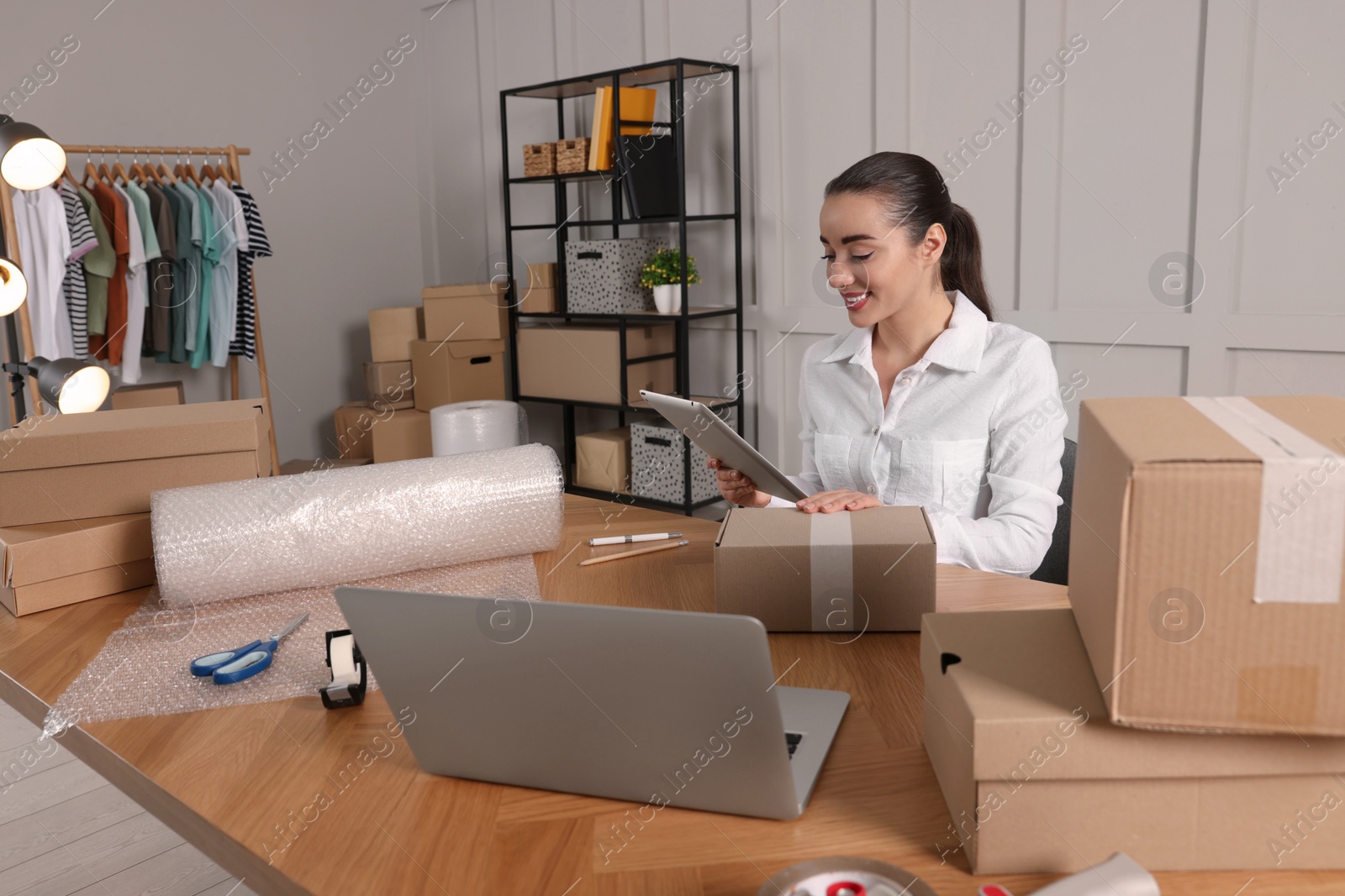 Photo of Seller with tablet and parcel at workplace. Online store